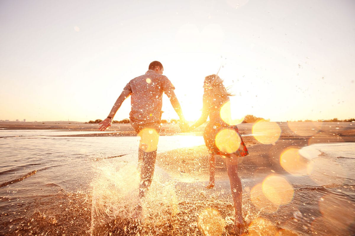 Wunscherfüllungsprogramm, Mann und Frau glücklich am Strand bei Sonnenschein